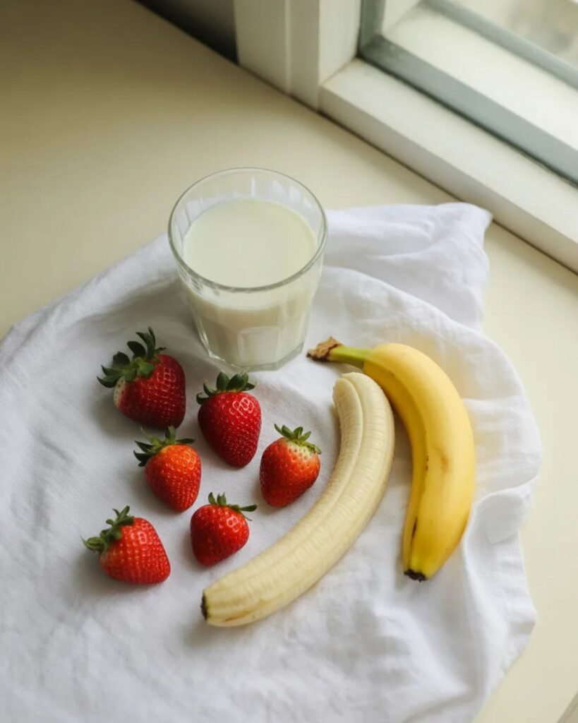 Ingredients for strawberry banana smoothie including fresh strawberries banana and milk