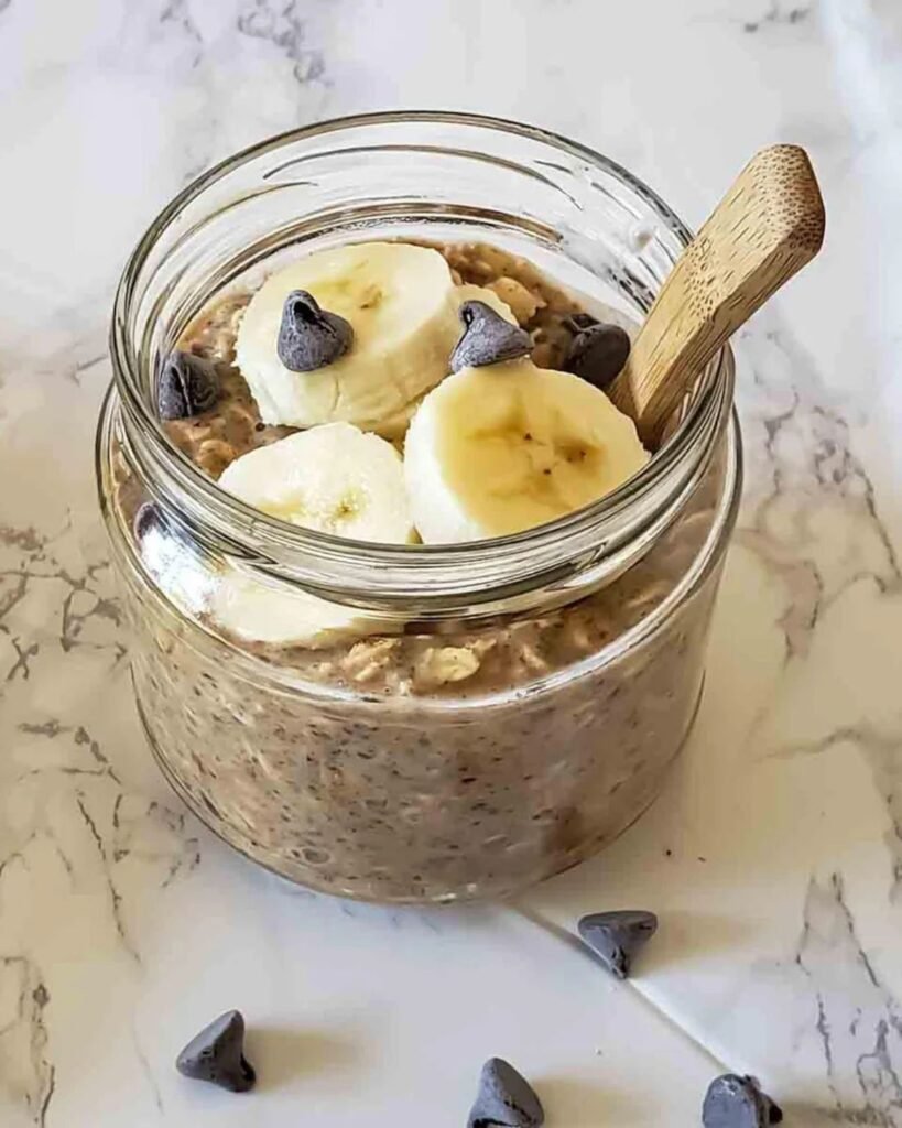 High protein overnight oats in a glass jar topped with strawberries and chia seeds on a kitchen counter