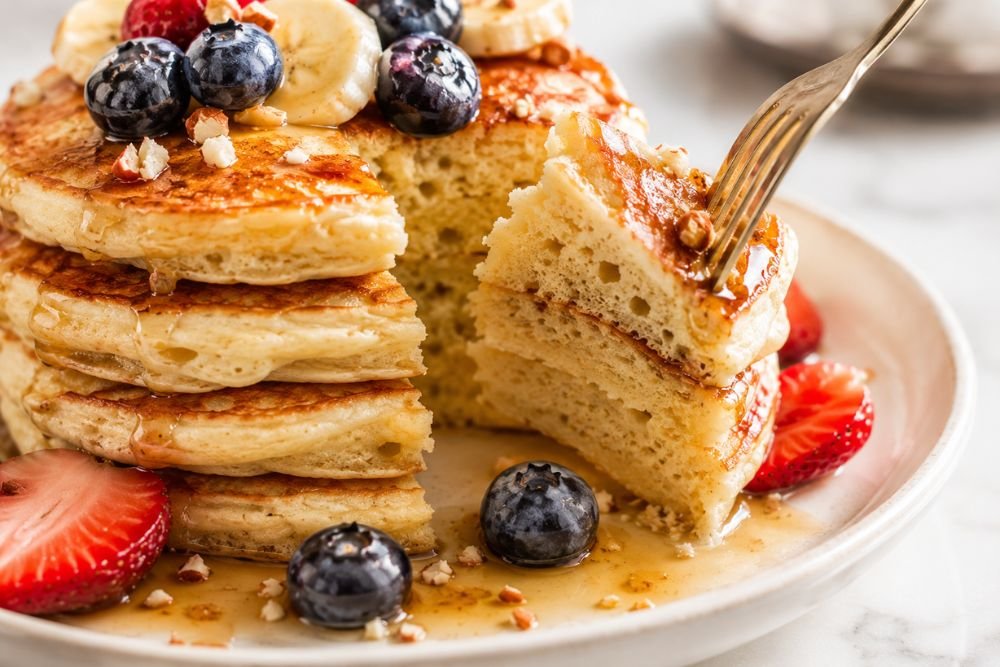 Soft fluffy pancake texture shown with a fork cutting into a golden pancake stack